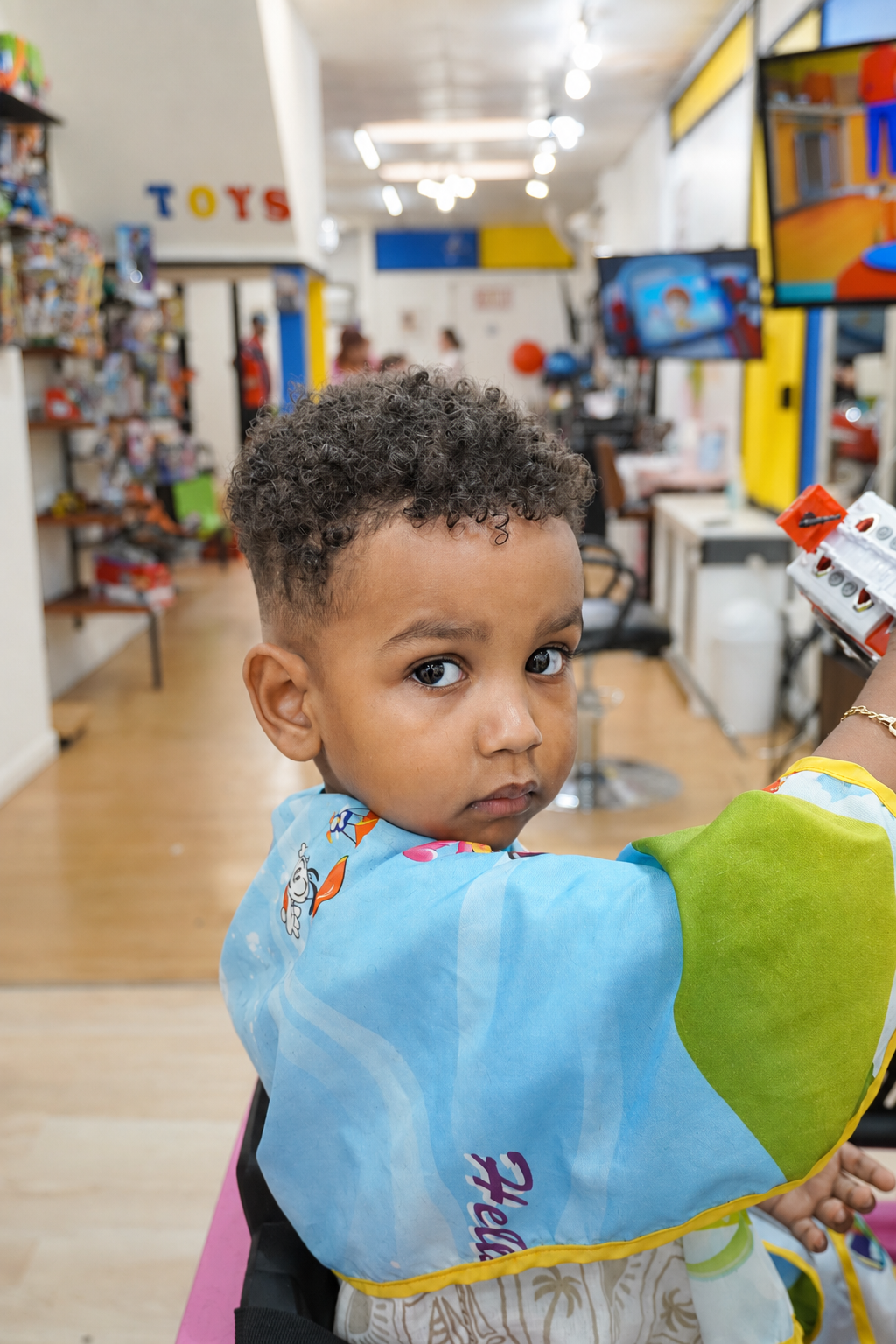 Toddler with a fresh curly fade wearing a cartoon cape